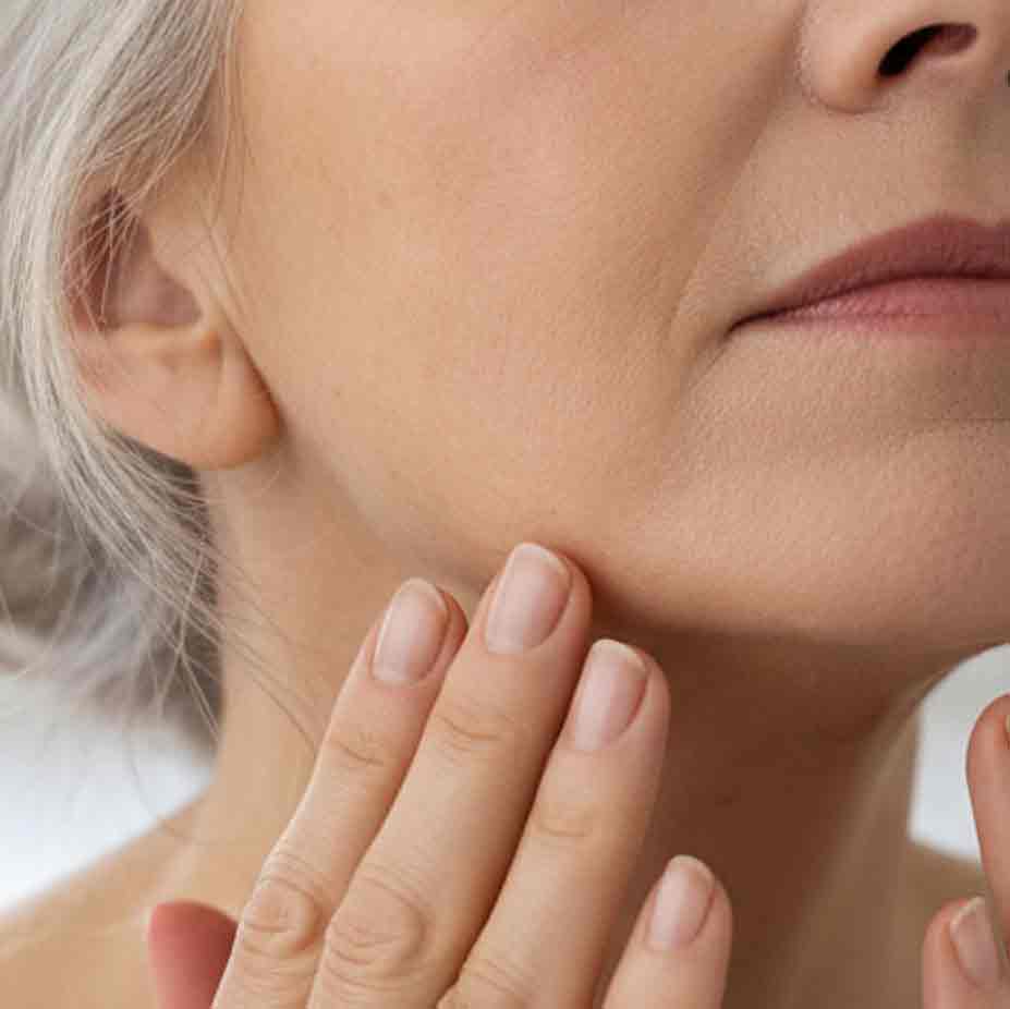 A woman touching the skin along her jawline